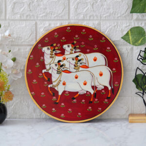 Crafted on a red plate, this pichwai portrays an enchanted encounter between a playful cow and a delicate lotus flower.